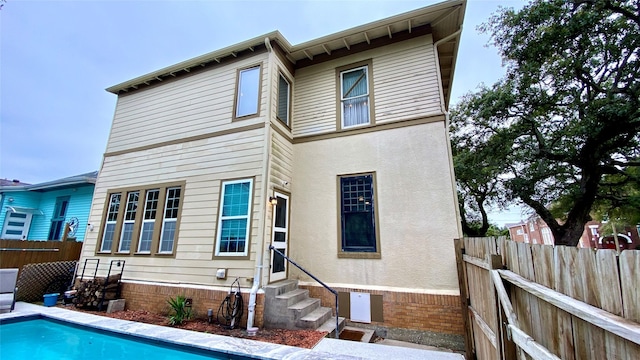 rear view of house featuring a fenced in pool