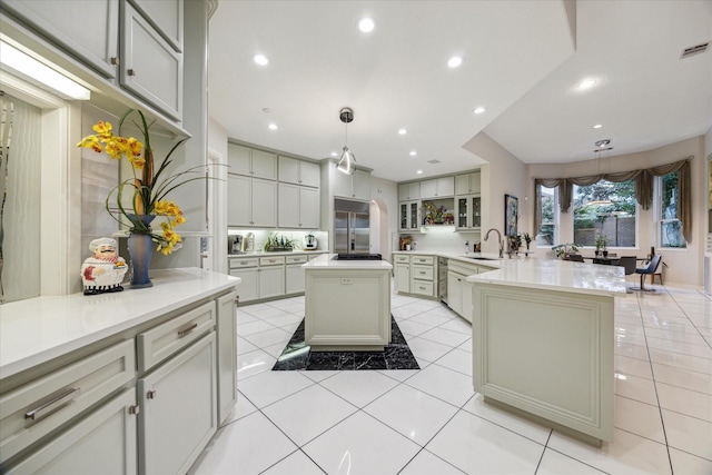 kitchen featuring light tile patterned flooring, recessed lighting, a peninsula, a sink, and stainless steel built in fridge