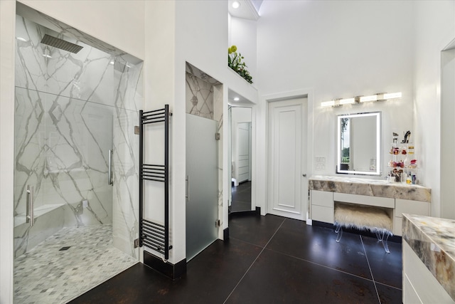 bathroom featuring a high ceiling, a marble finish shower, and vanity