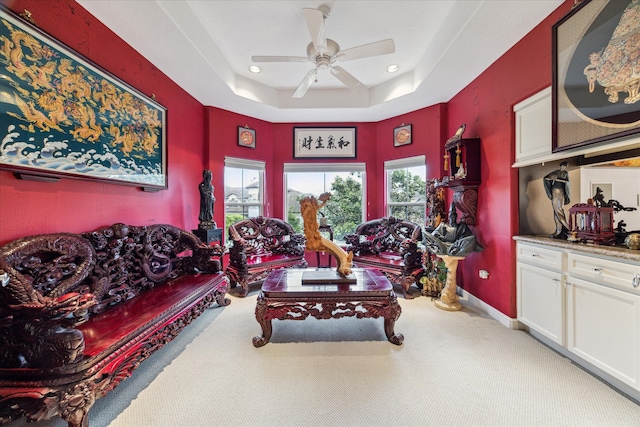 living room with carpet floors, a tray ceiling, plenty of natural light, and baseboards