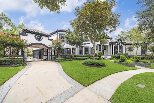 view of front of house with fence, a tiled roof, a gate, stucco siding, and a front yard