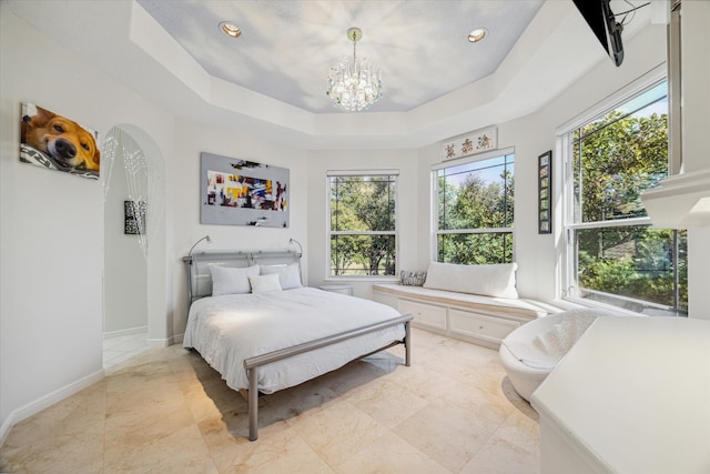 bedroom featuring an inviting chandelier, baseboards, arched walkways, and a tray ceiling