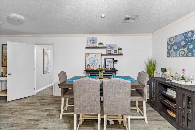 dining room with a textured ceiling, crown molding, and wood-type flooring