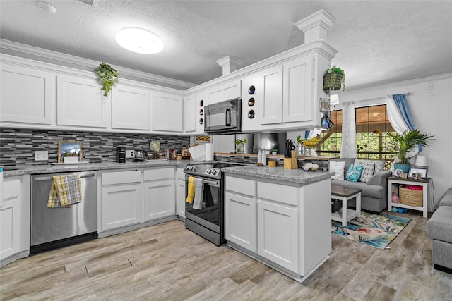 kitchen with crown molding, appliances with stainless steel finishes, white cabinetry, and light hardwood / wood-style floors