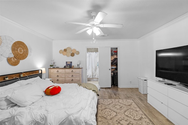 bedroom with light wood-type flooring, ceiling fan, a spacious closet, and crown molding