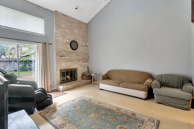 living room featuring light hardwood / wood-style flooring, high vaulted ceiling, and a brick fireplace