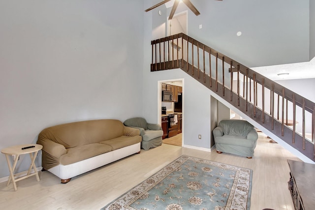 living room featuring ceiling fan, high vaulted ceiling, and light hardwood / wood-style floors