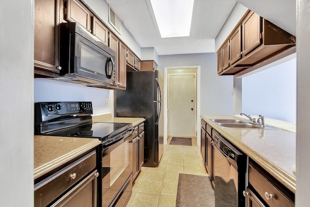 kitchen featuring black appliances, a skylight, light tile patterned floors, and sink