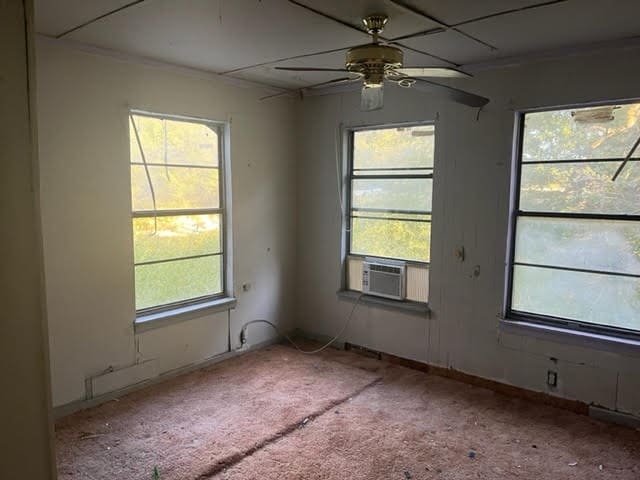 empty room featuring cooling unit, ceiling fan, and carpet