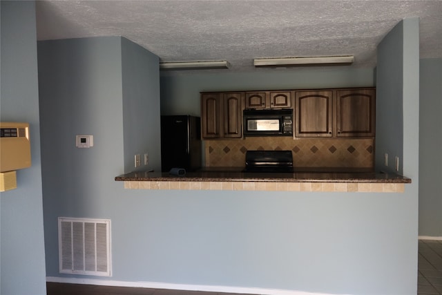 kitchen featuring black appliances, a textured ceiling, backsplash, and tile patterned floors