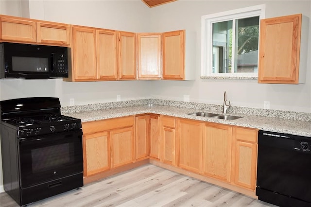 kitchen with light brown cabinetry, light hardwood / wood-style flooring, light stone countertops, sink, and black appliances