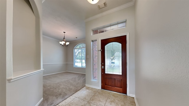 tiled entrance foyer featuring ornamental molding and an inviting chandelier