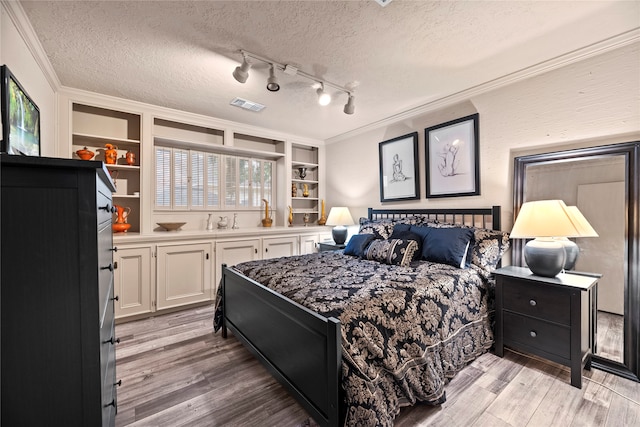 bedroom with a textured ceiling, crown molding, light hardwood / wood-style flooring, and multiple windows