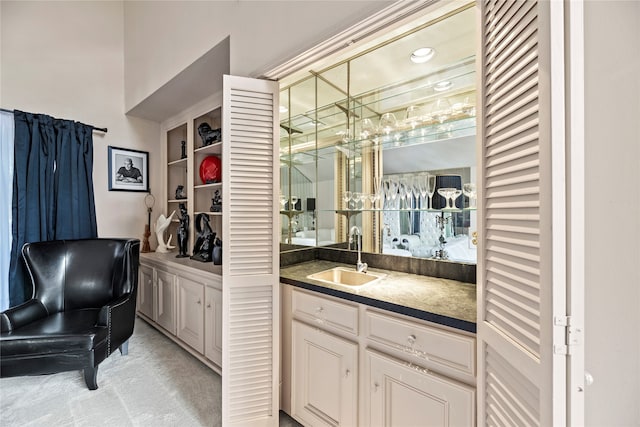 bar featuring light colored carpet, white cabinetry, and sink