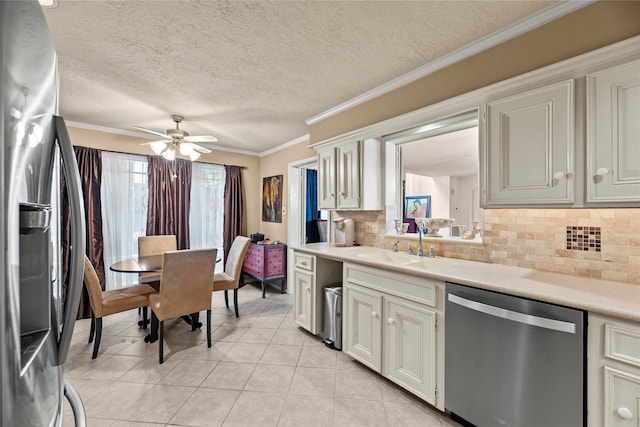 kitchen featuring a textured ceiling, backsplash, crown molding, stainless steel appliances, and ceiling fan