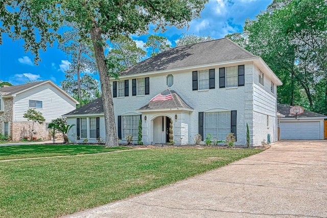 colonial house with a garage, a front yard, and an outbuilding