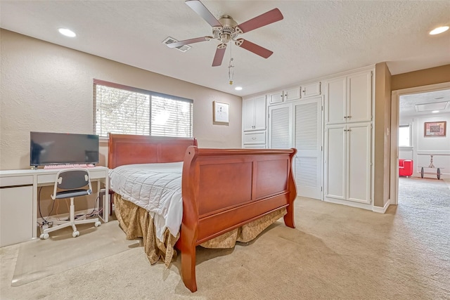 carpeted bedroom with a textured ceiling, ceiling fan, and a closet