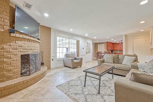 tiled living room featuring a fireplace and brick wall