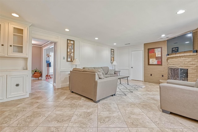 living room with a fireplace, ornamental molding, and light tile patterned floors