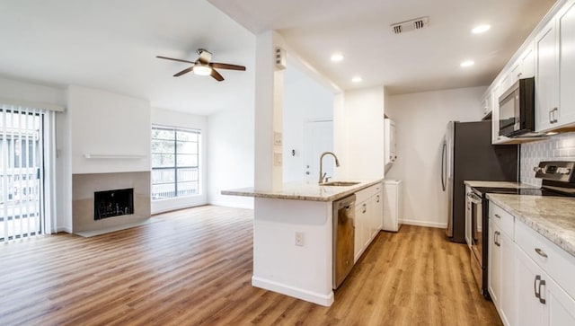 kitchen with white cabinetry, appliances with stainless steel finishes, light stone counters, and sink