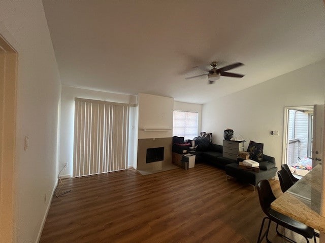 living area with lofted ceiling, ceiling fan, wood finished floors, and a fireplace with flush hearth