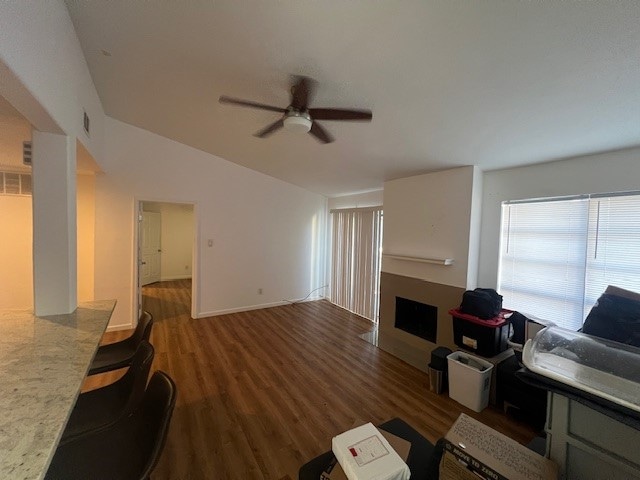 living room with ceiling fan, vaulted ceiling, and dark hardwood / wood-style flooring