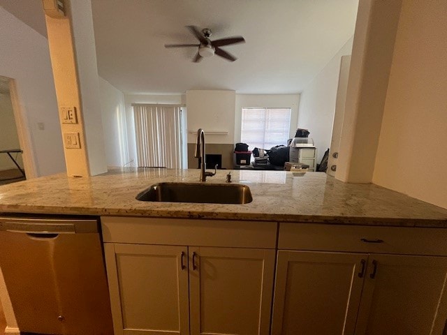 kitchen featuring light stone counters, ceiling fan, sink, kitchen peninsula, and stainless steel dishwasher