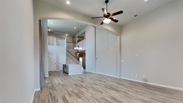 unfurnished living room with light hardwood / wood-style flooring, sink, and ceiling fan with notable chandelier