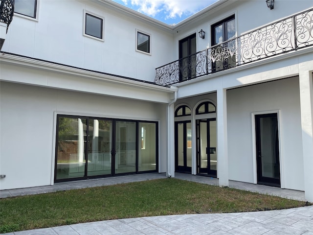 back of house featuring a balcony and a yard