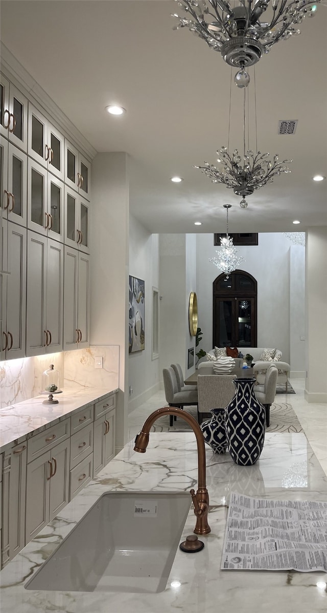 bathroom featuring backsplash, a chandelier, and sink