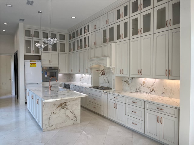 kitchen with hanging light fixtures, light stone counters, stainless steel appliances, a chandelier, and a kitchen island with sink