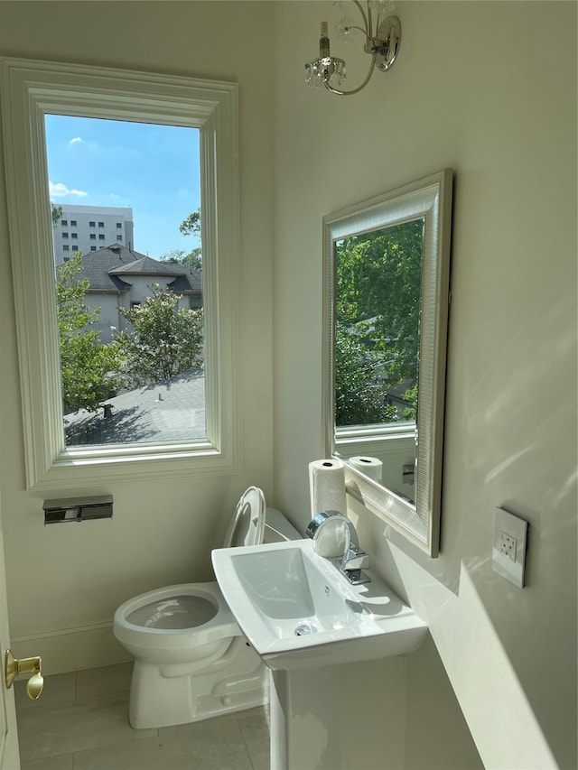 bathroom featuring tile patterned flooring, toilet, and a chandelier