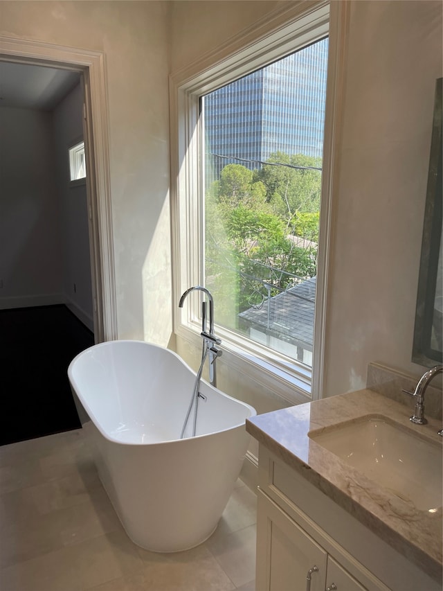 bathroom with tile patterned floors, a bathtub, and vanity