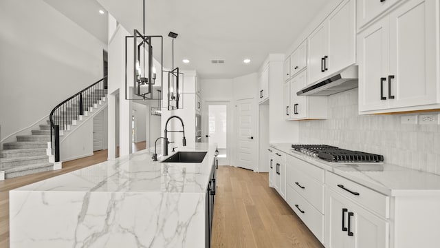 kitchen featuring white cabinetry, sink, pendant lighting, and stainless steel gas stovetop