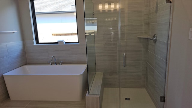 bathroom featuring plus walk in shower, tile walls, and tile patterned floors