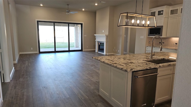 kitchen featuring ceiling fan, sink, white cabinetry, and light stone countertops