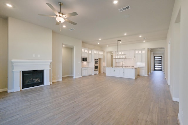 9715 Hunters Run Dr, Missouri City, TX 77459 - unfurnished living room featuring visible vents, light wood finished floors, recessed lighting, ceiling fan, and a glass covered fireplace