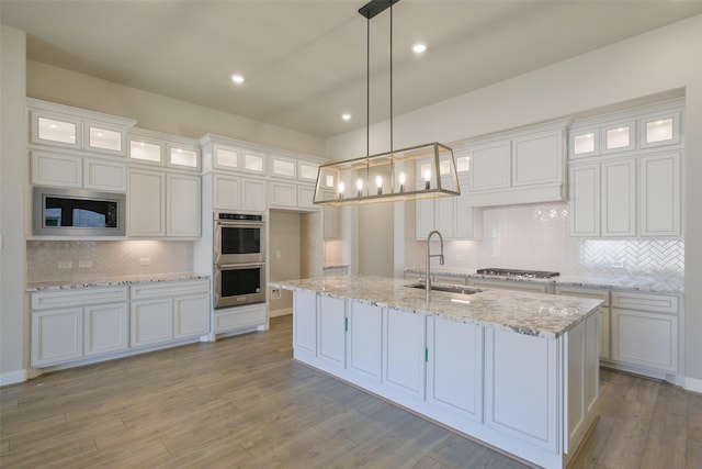 9715 Hunters Run Dr, Missouri City, TX 77459 - kitchen featuring an island with sink, a sink, stainless steel appliances, white cabinets, and light wood-style floors