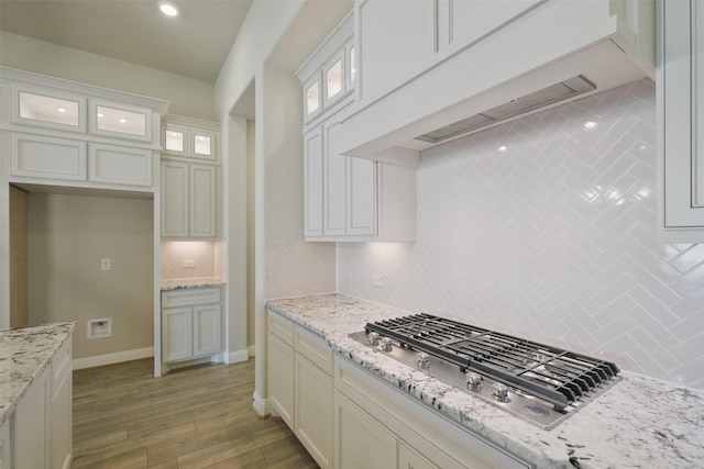 9715 Hunters Run Dr, Missouri City, TX 77459 - kitchen featuring light wood finished floors, backsplash, baseboards, custom range hood, and stainless steel gas stovetop