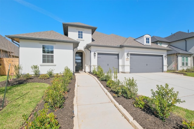 view of front of property featuring a garage, roof with shingles, driveway, and stucco siding