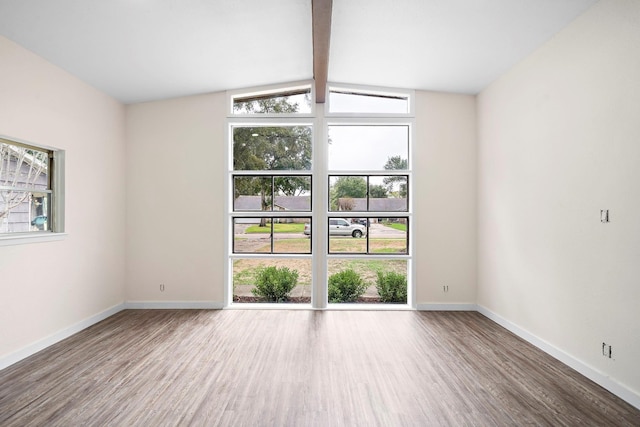 spare room featuring hardwood / wood-style floors and vaulted ceiling with beams