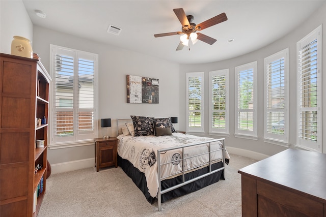 bedroom with ceiling fan, light colored carpet, and multiple windows