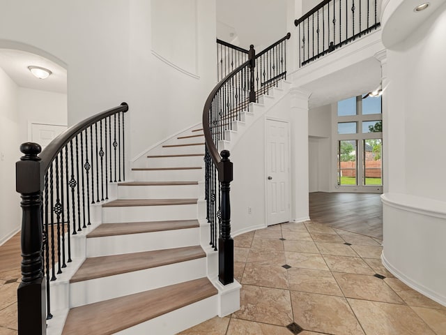 staircase with a high ceiling and hardwood / wood-style flooring