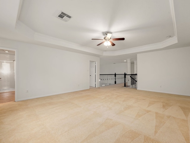 carpeted spare room with a raised ceiling, ceiling fan, and crown molding