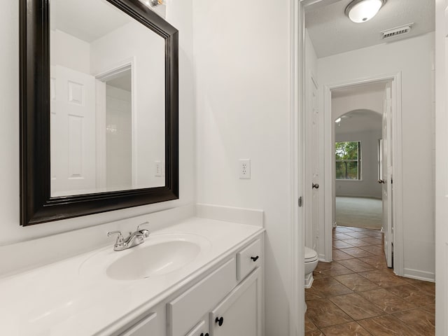 bathroom featuring vanity, toilet, and a textured ceiling