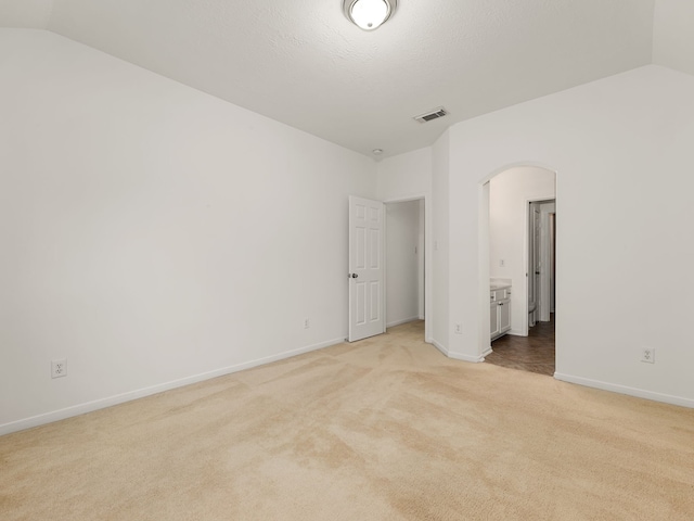 spare room with light colored carpet and lofted ceiling