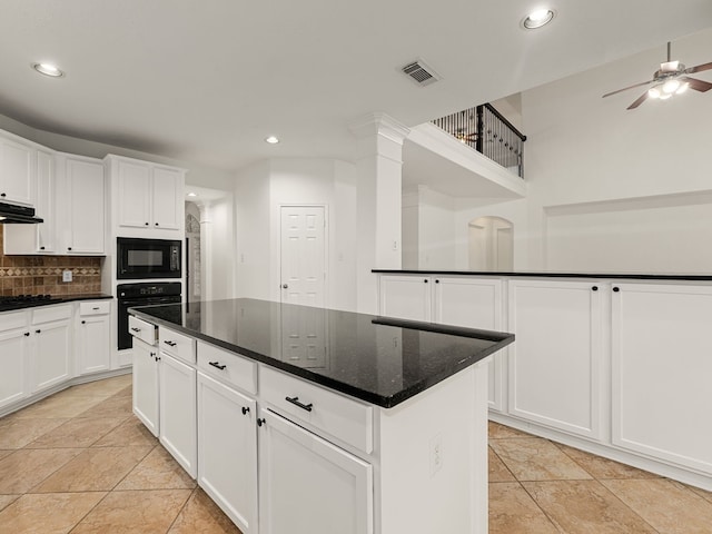 kitchen with tasteful backsplash, black appliances, dark stone countertops, a center island, and white cabinetry