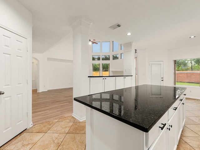 kitchen featuring a center island, white cabinetry, light hardwood / wood-style flooring, and dark stone countertops