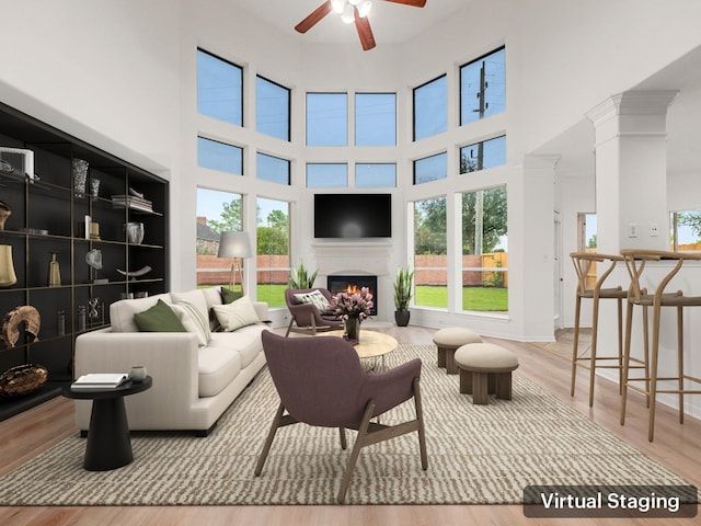 living room with ceiling fan, light wood-type flooring, and a towering ceiling