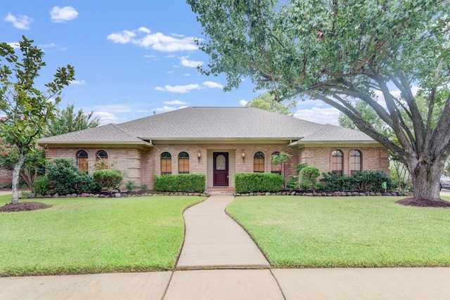 single story home with a shingled roof, brick siding, and a front lawn